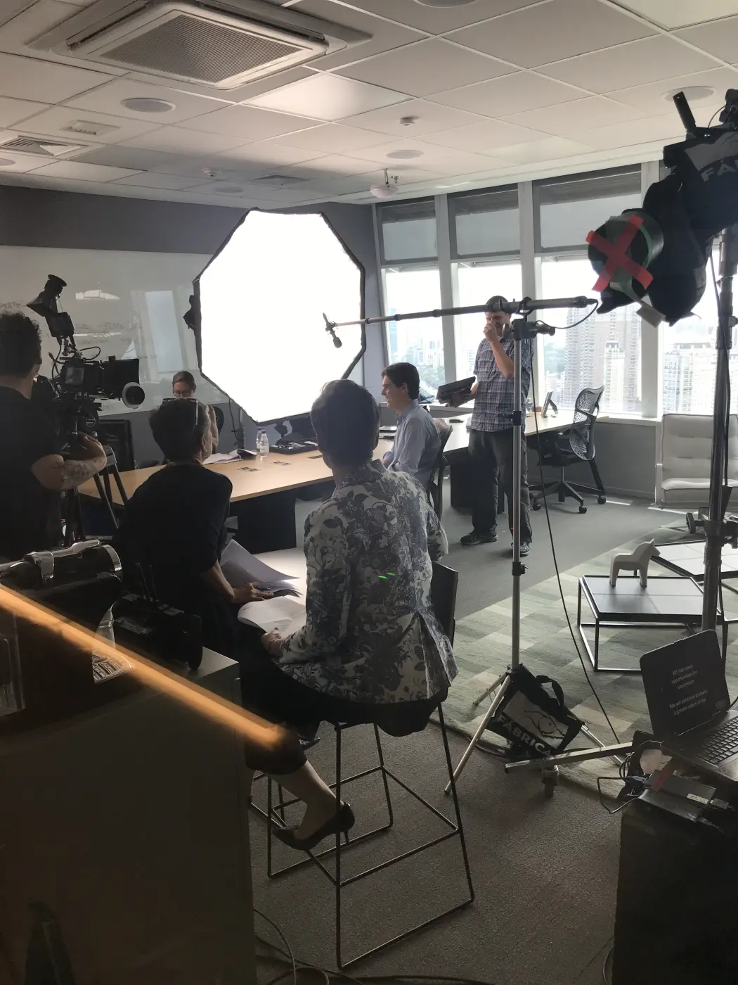Equipe com câmera, luz e microfone montados durante uma gravação em um escritório